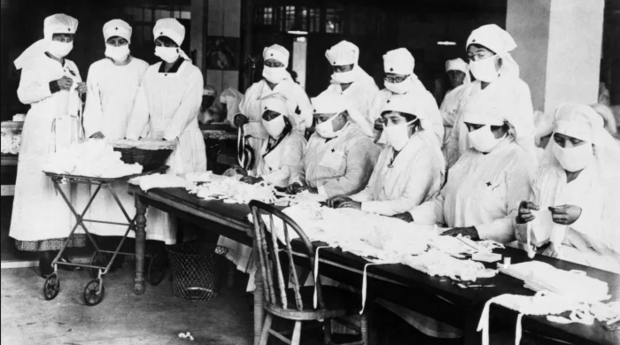 Women working for the Red Cross make masks during the pandemic flu in 1918.png